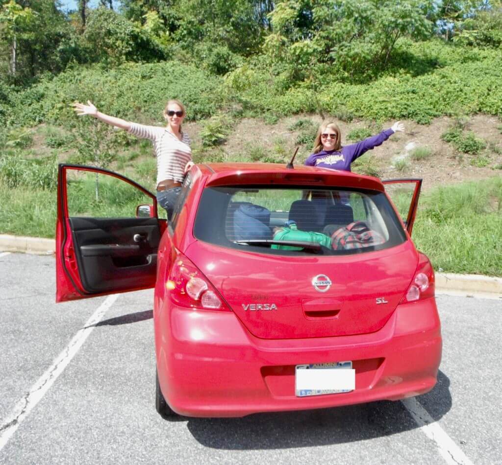 Gwen and Molly with outstretched arms in a red car