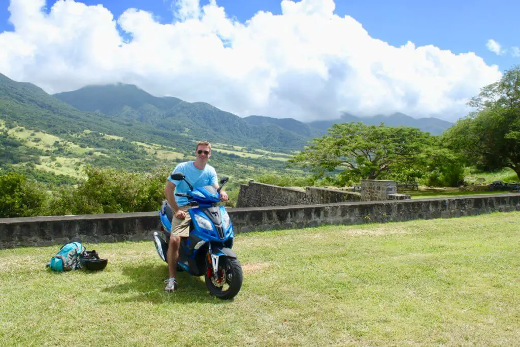 M on a scooter with the green mountains of St. Kitts in the background - the perfect St. Kitts  DIY shore excursion!