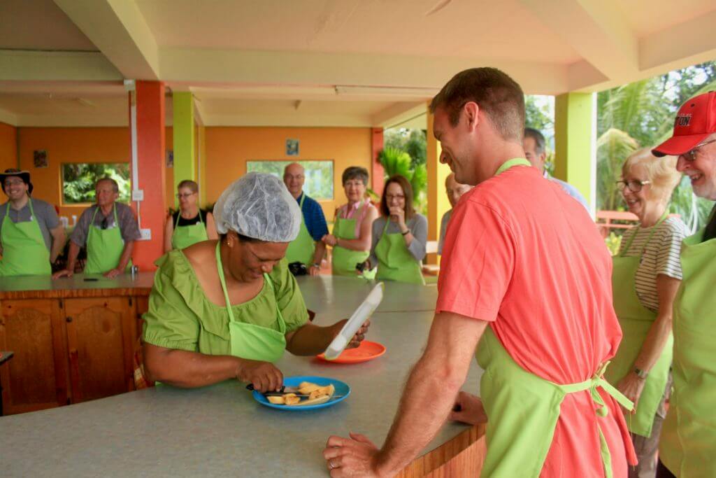 Dominican woman laughing at M's terribly-cut banana pieces with others looking on