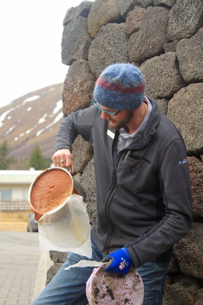 Snorri revealing bread that had been baked in a ceramic pot underground.