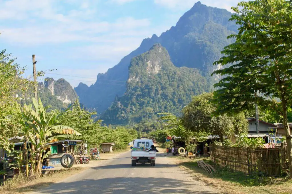 Truck on rural Laotian road with mountains beyond
