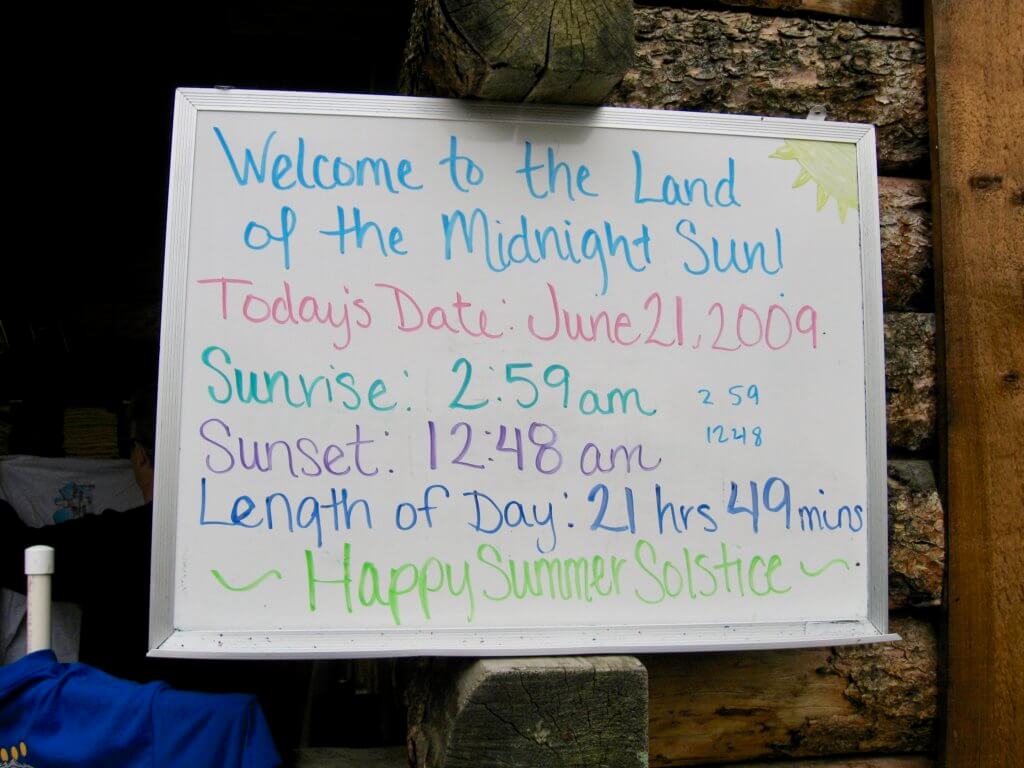 Solstice sign stating a 2:59 AM sunrise and 12:48 AM sunset. Add some sleeping aids to your Alaska packing list to help combat all that midnight sun.