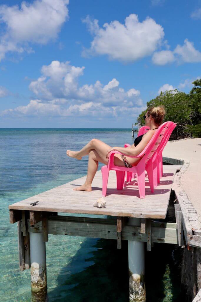 Brooke on a pink chair near the ocean on Bread and Butter Caye