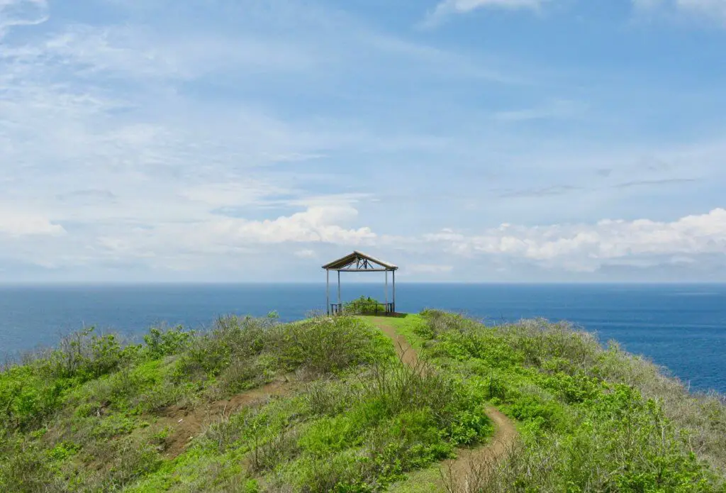 Open wooden hut on a green headland with the sea beyond