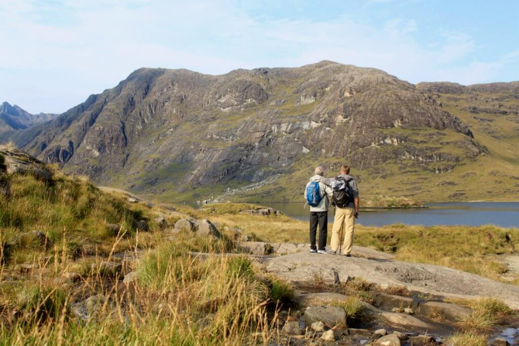 M and his dad in front of Loch Coruisk and the Cuillin Hills, a quieter spot away from the destinations on this Isle of Skye driving itinerary