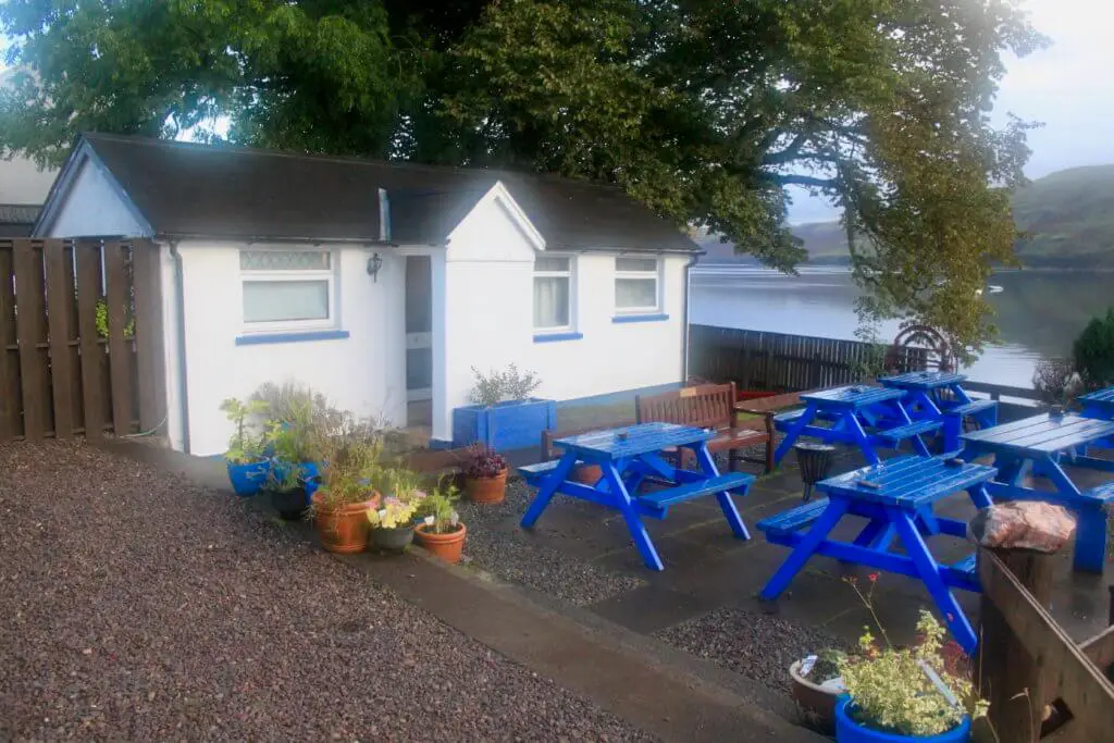 Small white cottage with blue picnic tables in front