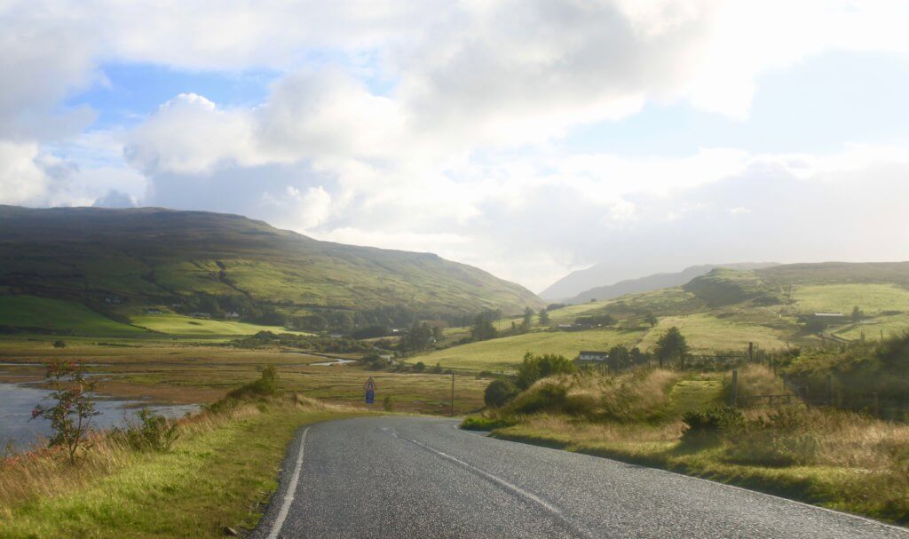 Road winding through the green and golden hills on an Isle of Skye driving itinerary.