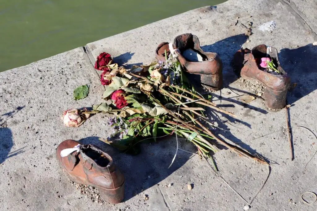 Flowers and candles placed with iron shoes in the Shoes on the Danube Bank memorial