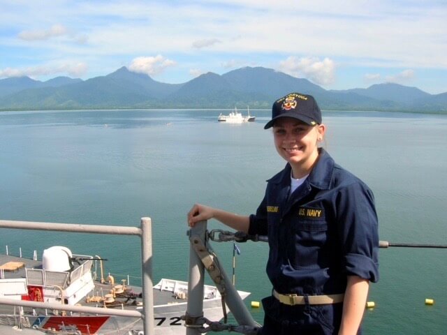 Ellen on ship with green mountains and ocean behind