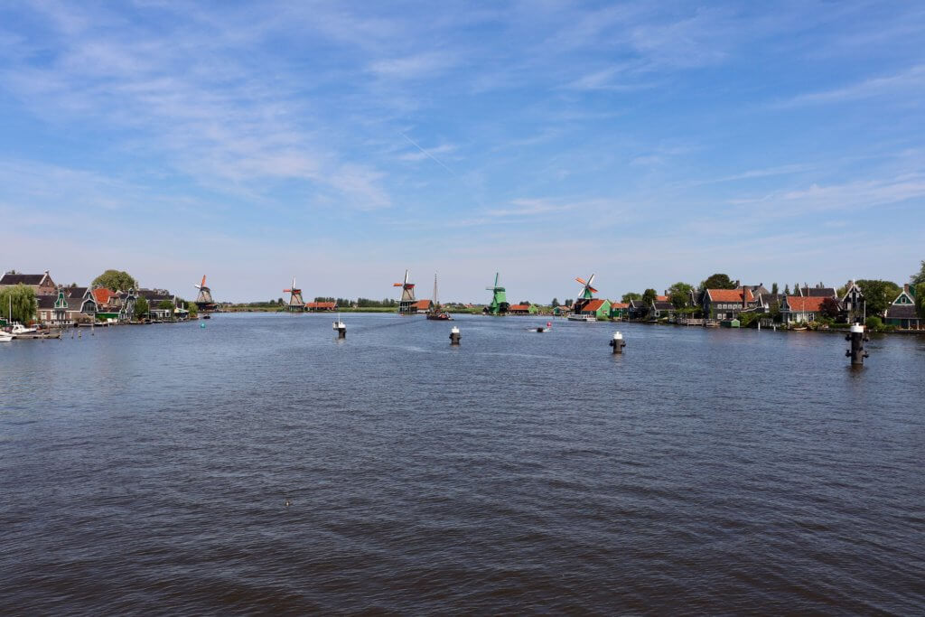 Colorful buildings and Zaanse Schans windmills along the river.