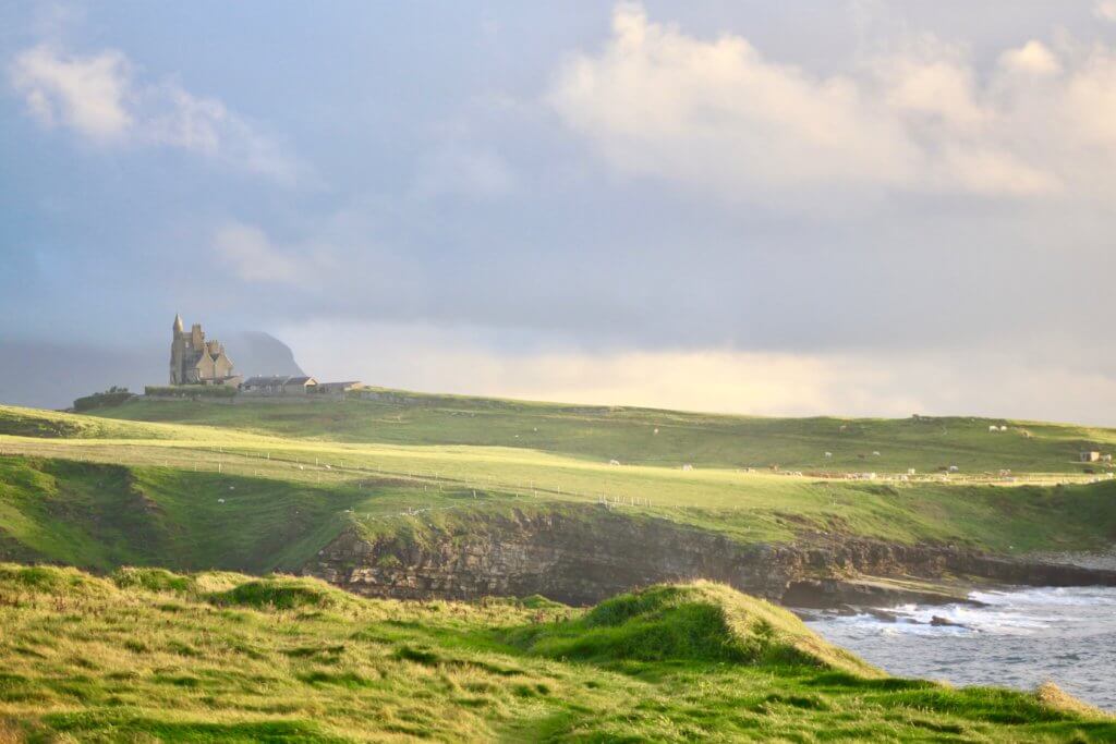 Green sea cliffs, turbulent water, and Classiebawn Castle