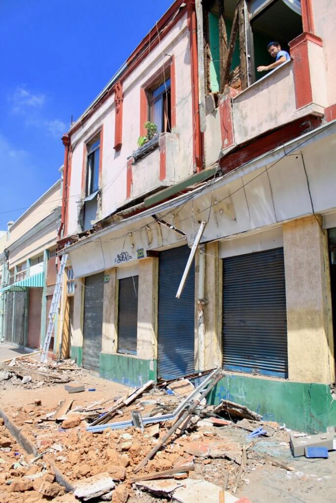 Building damaged by earthquake, with broken windows and rubble on street