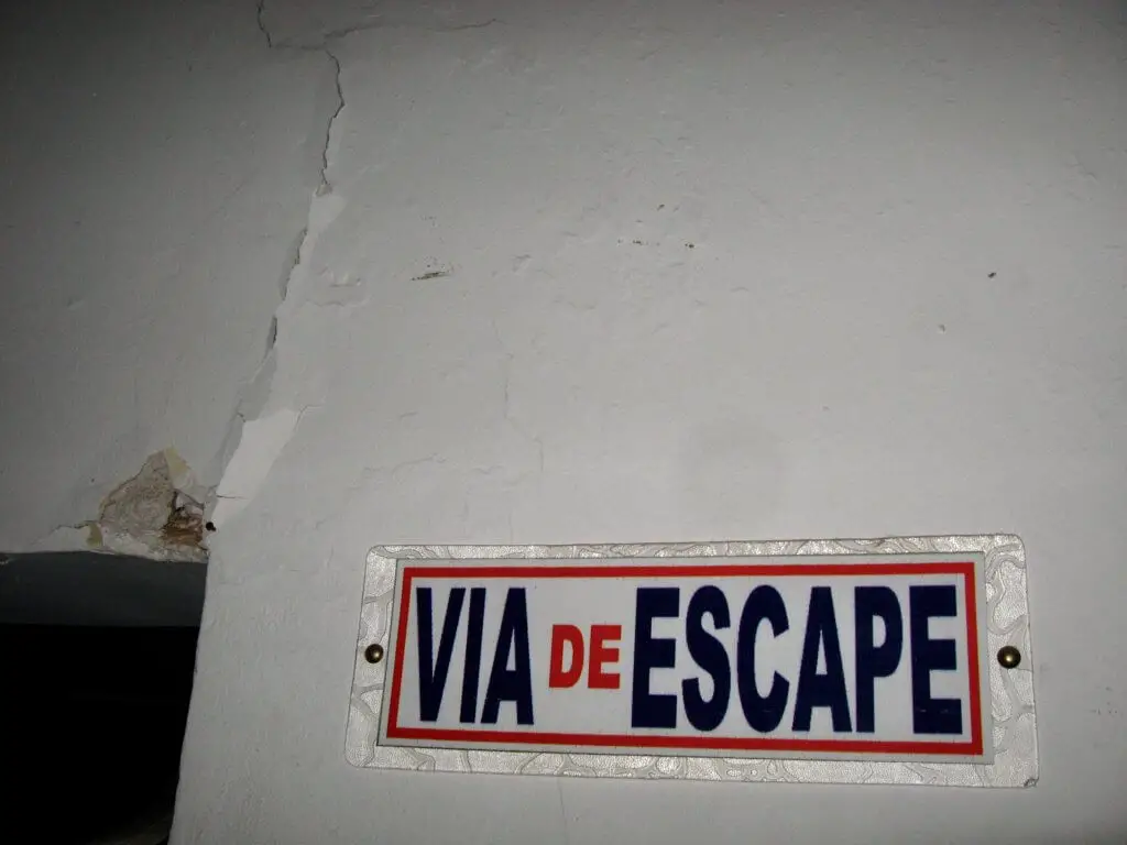 Cracked wall next to "Via de Escape" ("Escape Route") sign