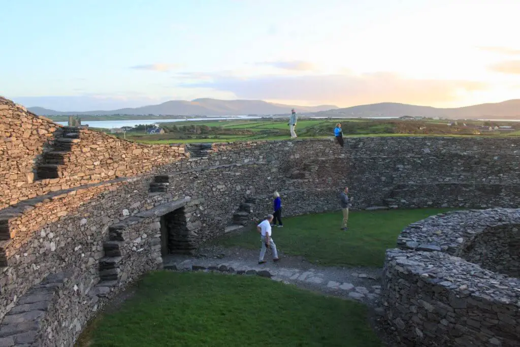 People wandering around stone structures inside ring fort