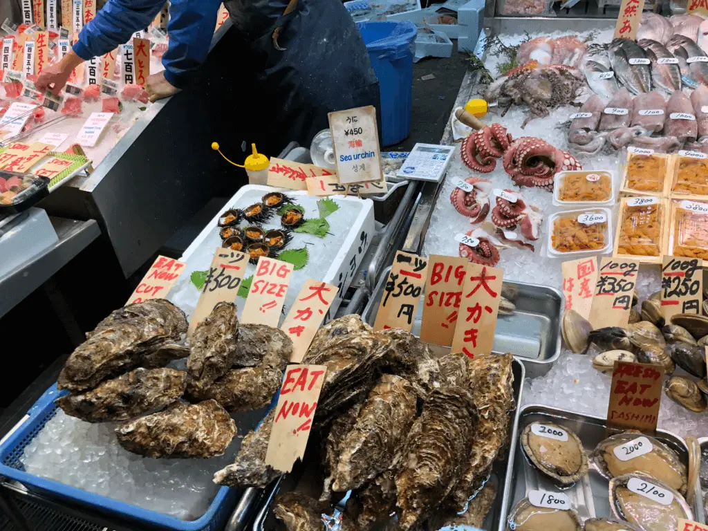 Oysters, octopus, sea urchins, and other seafood products on ice at a market