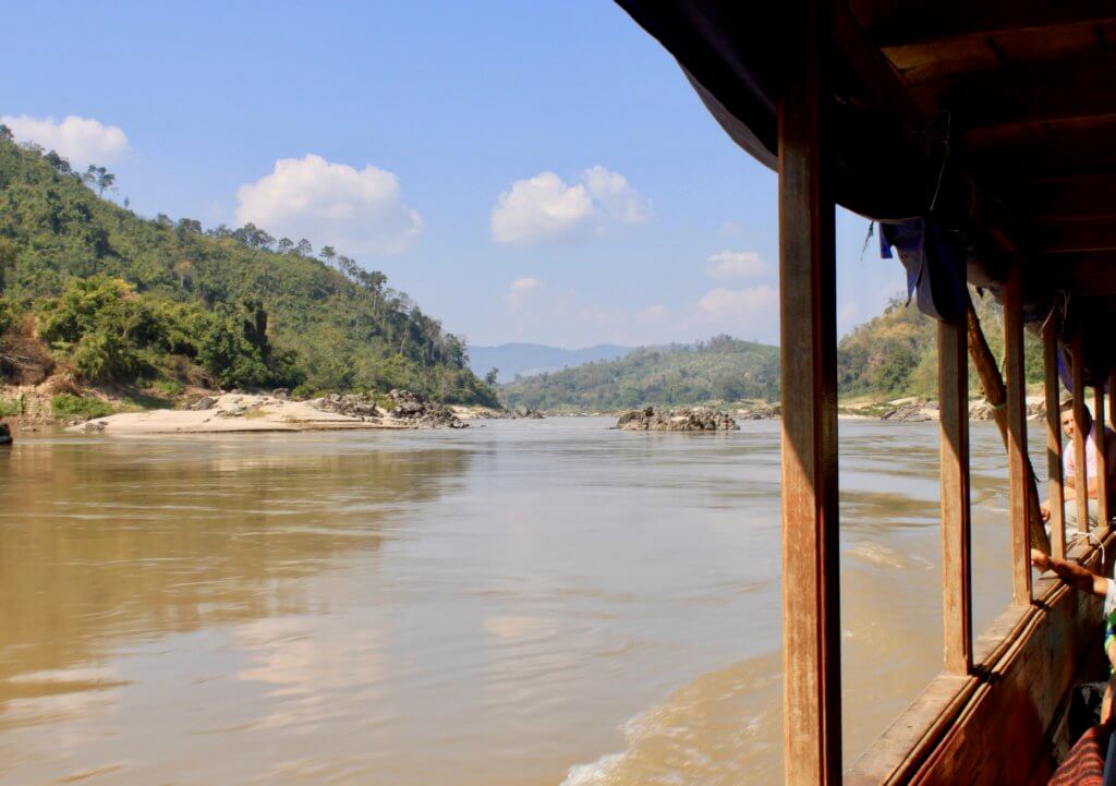 View of the river and green hillsides through the open longboat window