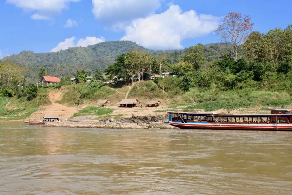 Another longboat docked beside a village perched on a green hillside. Just some of the beautiful scenery on a Mekong River cruise in Laos!
