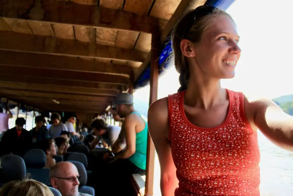 Gwen sitting in the window of the longboat and smiling out at the scenery - loving life on a Mekong River cruise in Laos!