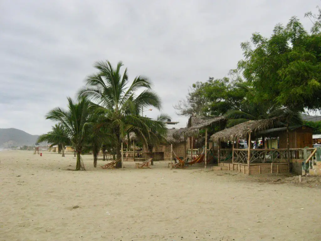 Thatch-roofed beach bars in the sand of Puerto Lopez