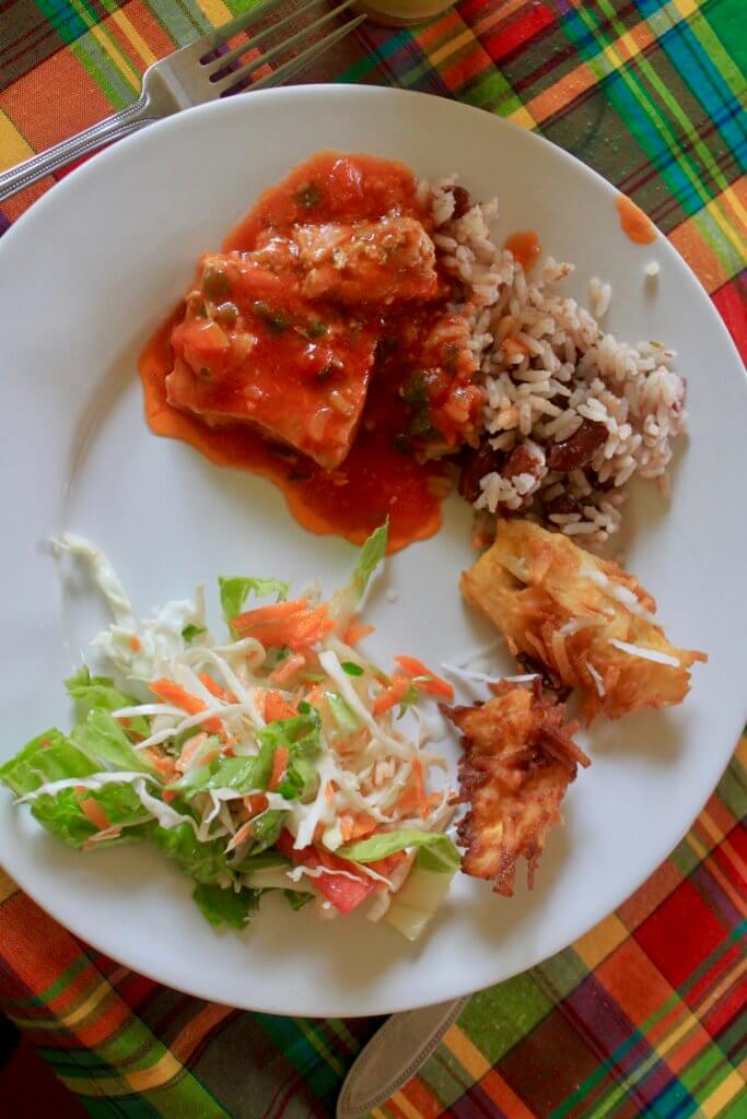 Creole food on a white plate on top of a colorful plaid tablecloth