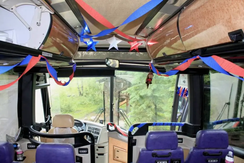 View from interior of tour bus out front windshield with streamers and stars and other patriotic decorations