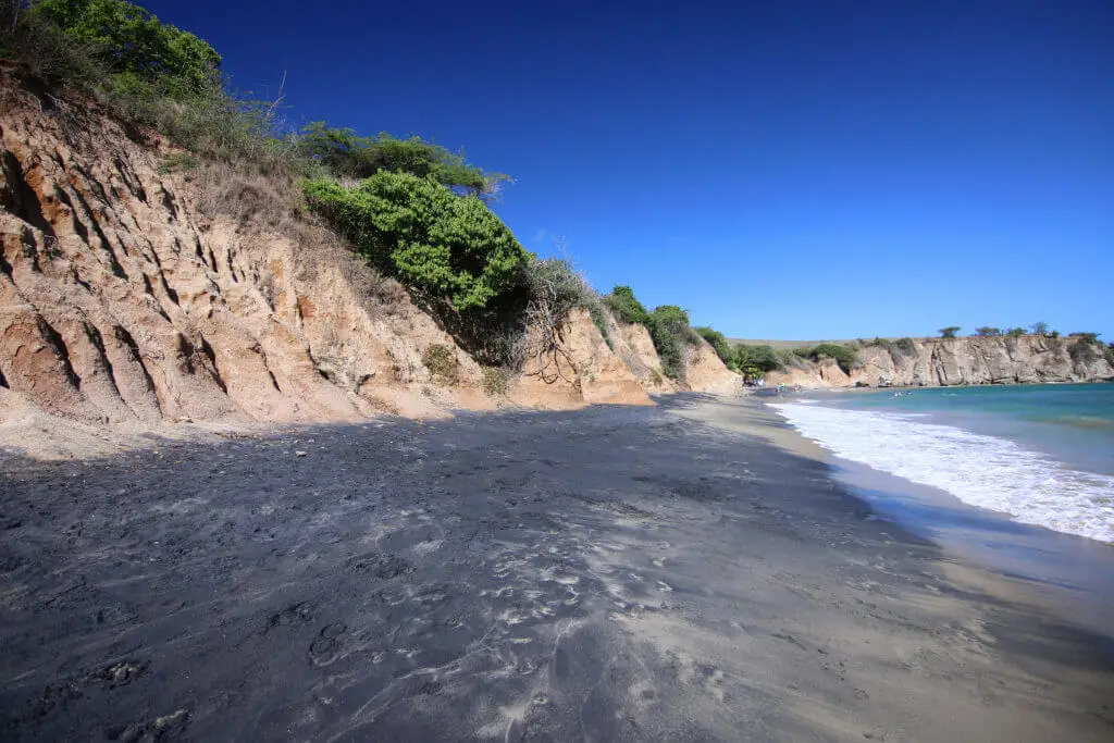 View of Playa Negra with black sand and tan-colored cliffs