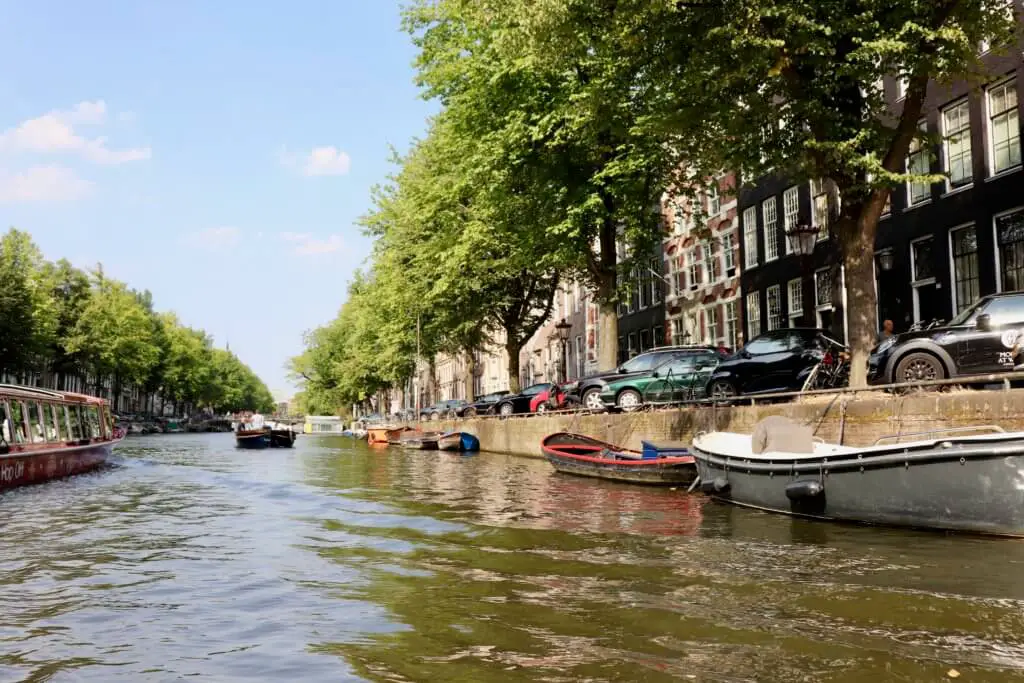Row houses shaded by leafy trees along the canals in in Amsterdam