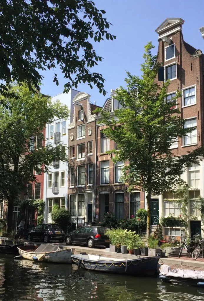Shaded row houses and boats along Amsterdam canal