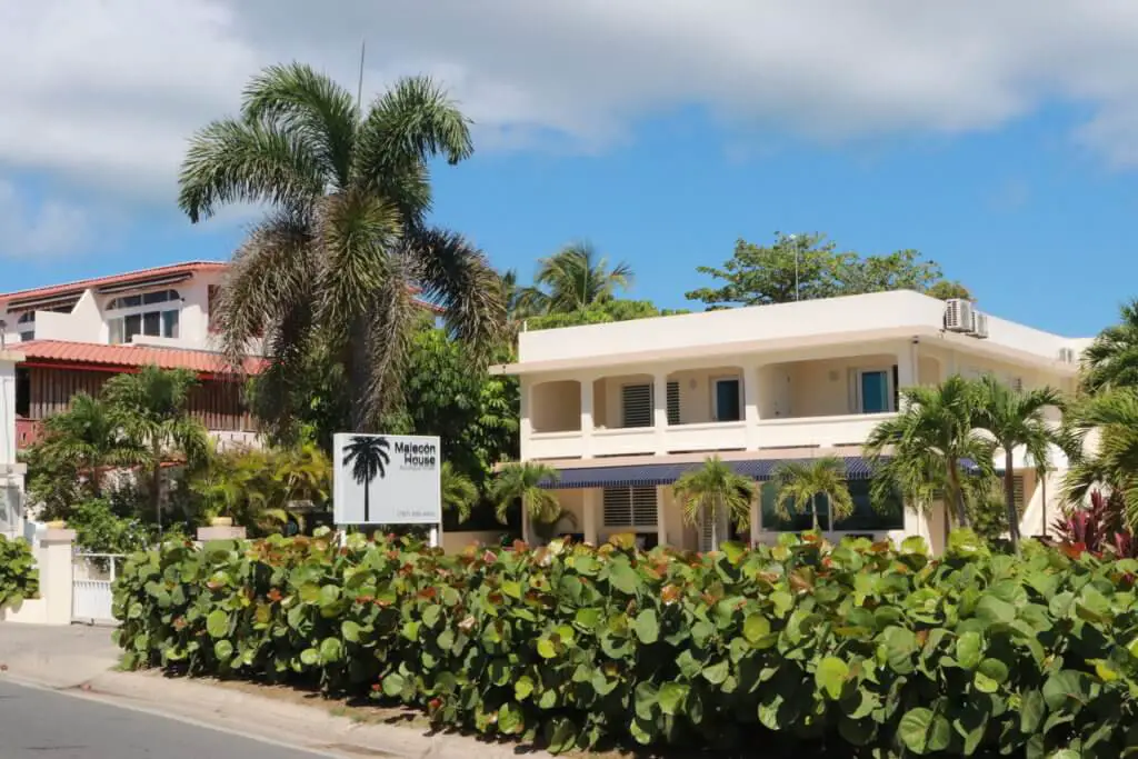 Front view of Malecon House ringed with palm trees and greenery