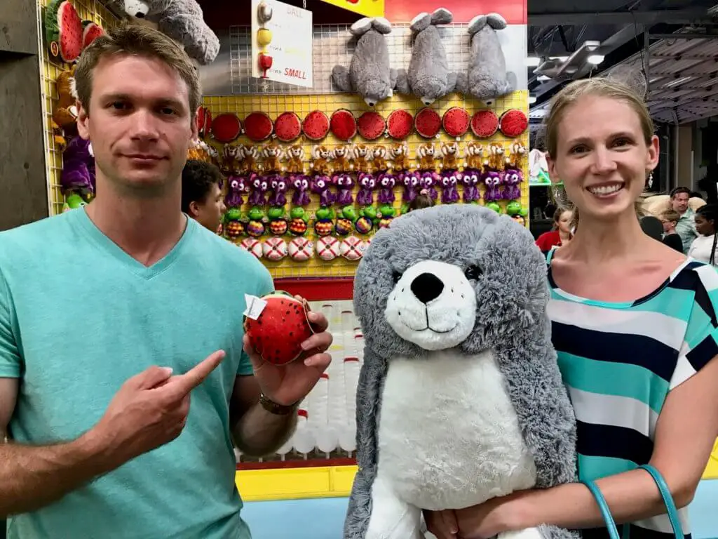 M holding a tiny watermelon stuffed animal beside Gwen, who is holding a giant stuffed seal