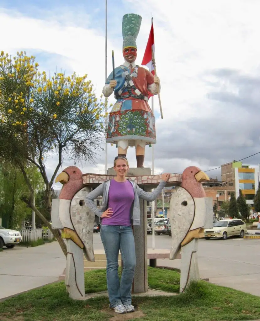 Gwen standing in front of a statue of parrots and man in native dress