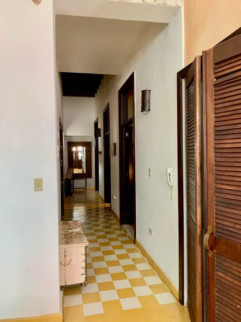 Hallway of hotel suite with yellow checked tile and dark wooden doors