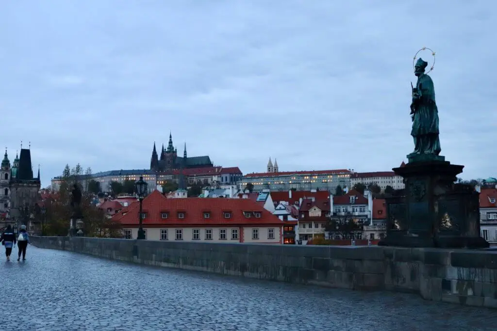 Statues and castle coming into view at dawn on the Charles Bridge