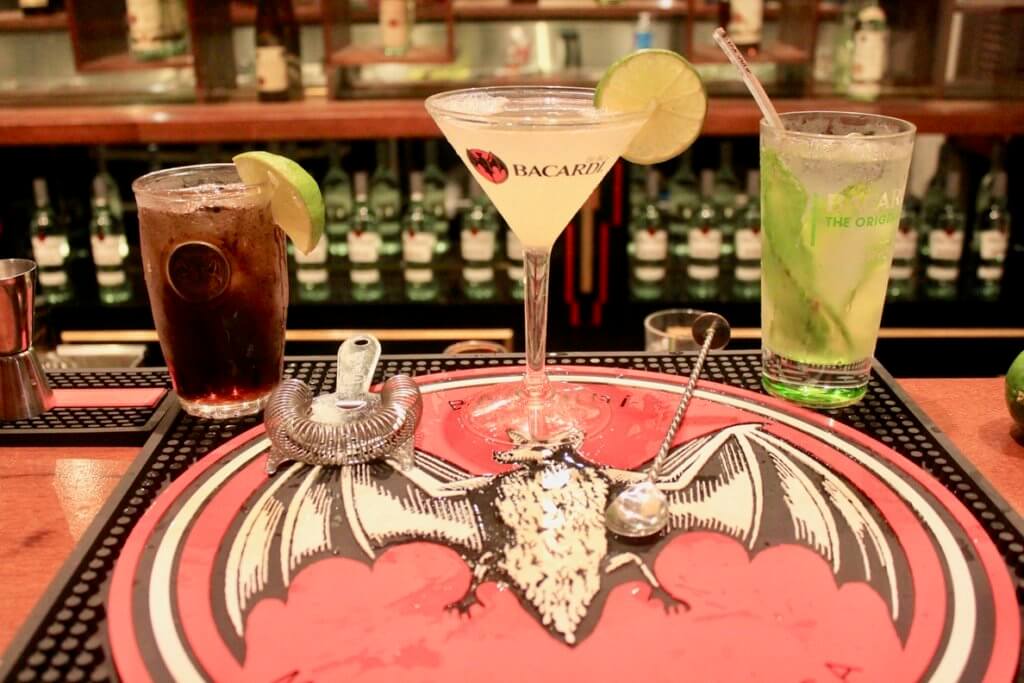 Mixed cocktails on a mat bearing the Bacardi bat logo