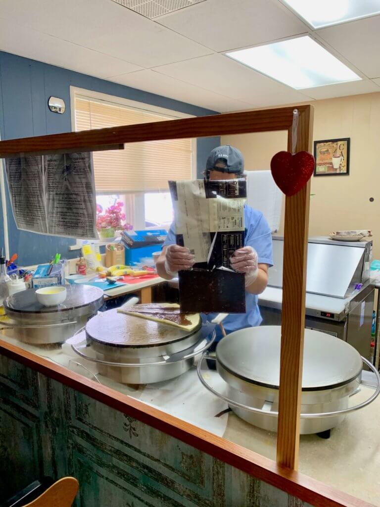 Man melting a giant chocolate bar onto crepes