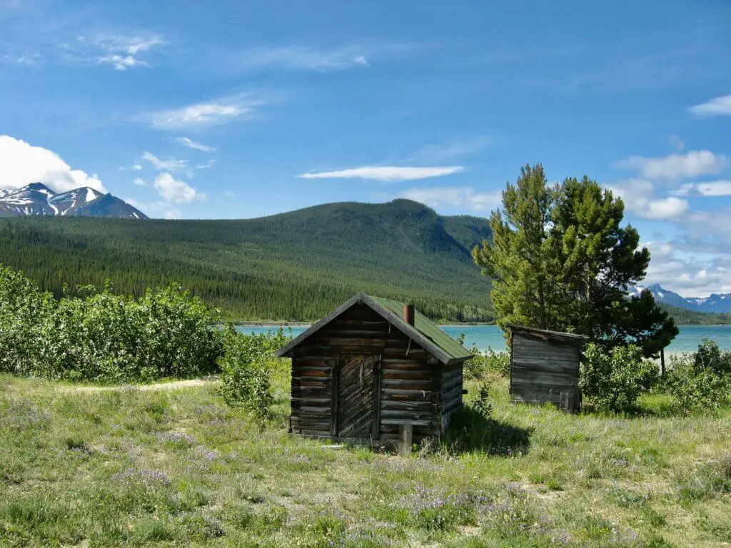 Small log cabin with mountains beyond outside Carcross, Yukon
