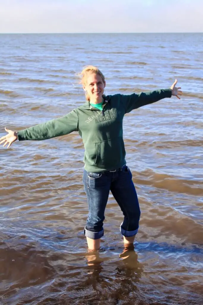 Gwen with arms spread wide ankle deep in the Arctic Ocean