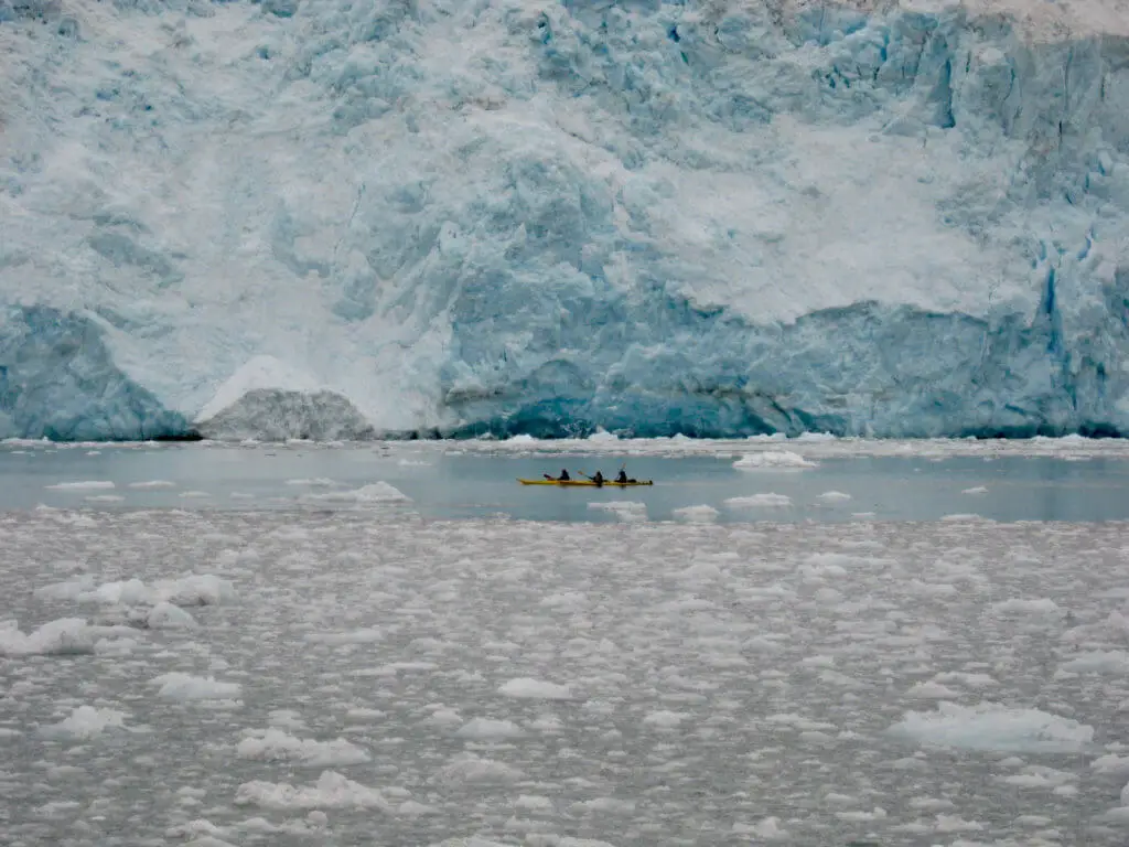 Tiny kayakers in front of a massive blue glacier. Kayaking is a great thing to put on your Alaska itinerary.