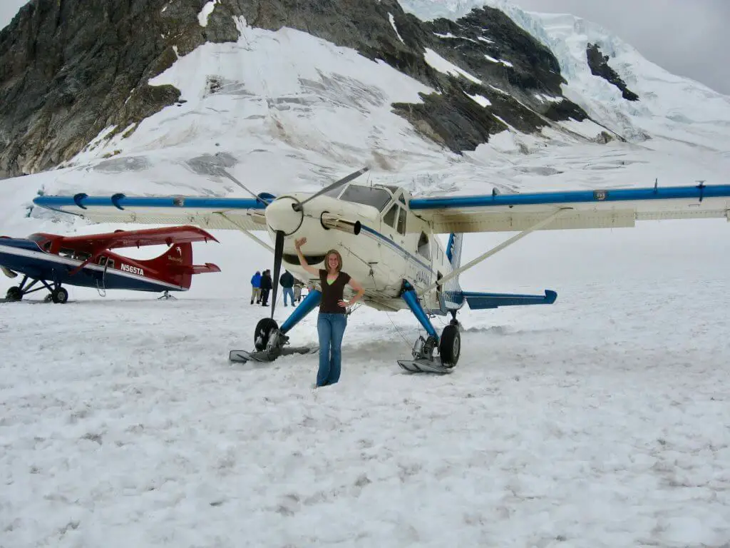 Gwen standing with a prop plane on a glacier