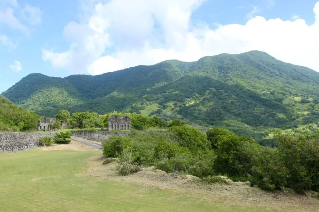 The green volcanic mountains of St. Kitts with fort ruins in the foreground. 