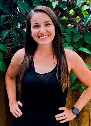 Charlotte smiling in front of a leafy green background