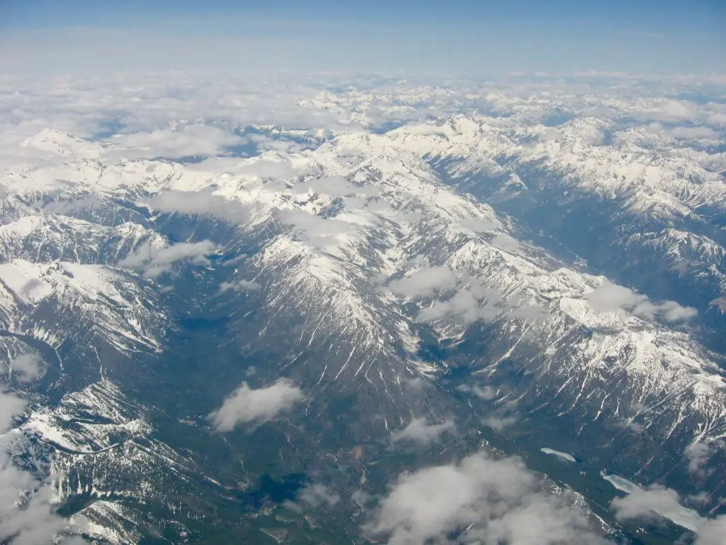 Snow-capped mountains as far as the eye can see as captured from a plane window