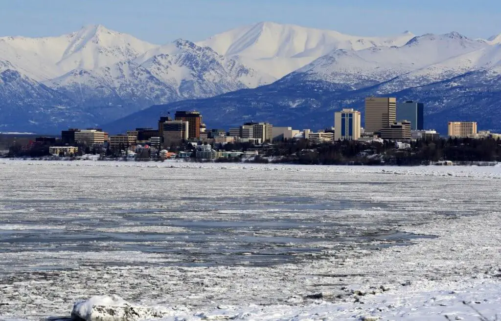 Anchorage skyline with snow-capped mountains beyond. Anchorage is a great first stop on your Alaska itinerary.