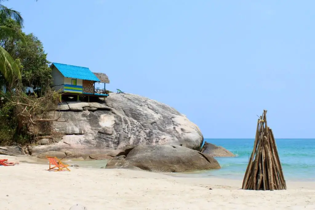 Bungalow perched on a huge boulder and bonfire pyre on the sand