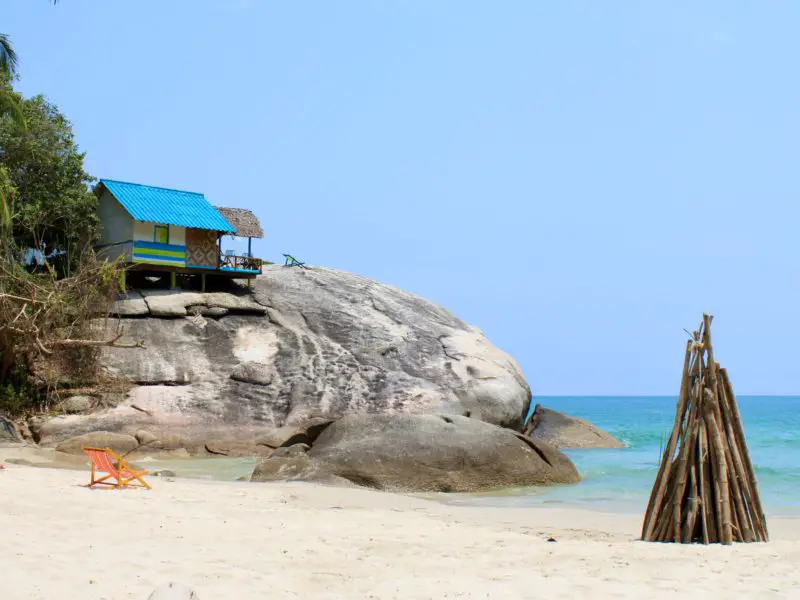 Bungalow perched on a huge boulder and bonfire pyre on the sand