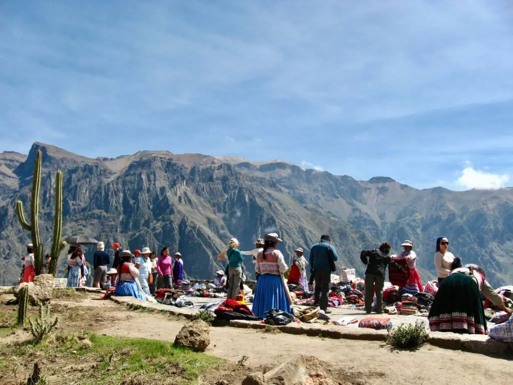 Indigenous women in traditional dress selling handicrafts and snacks along the canyon's rim