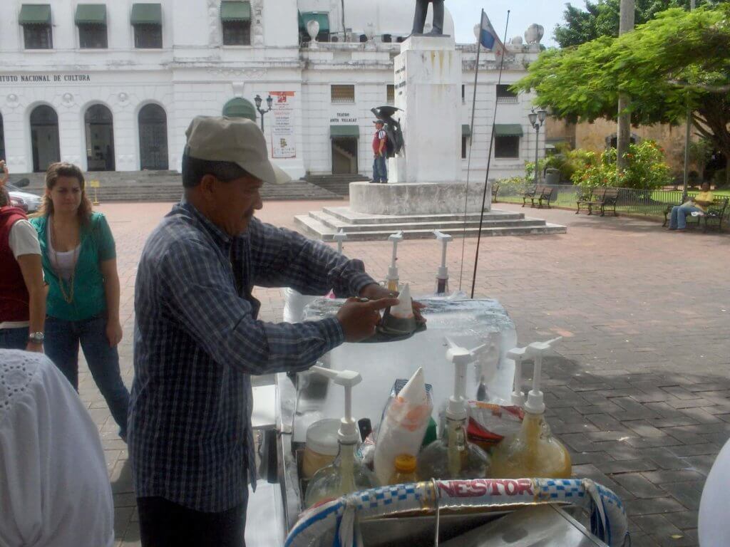 Raspado vendor making a shaved ice from a huge block of ice