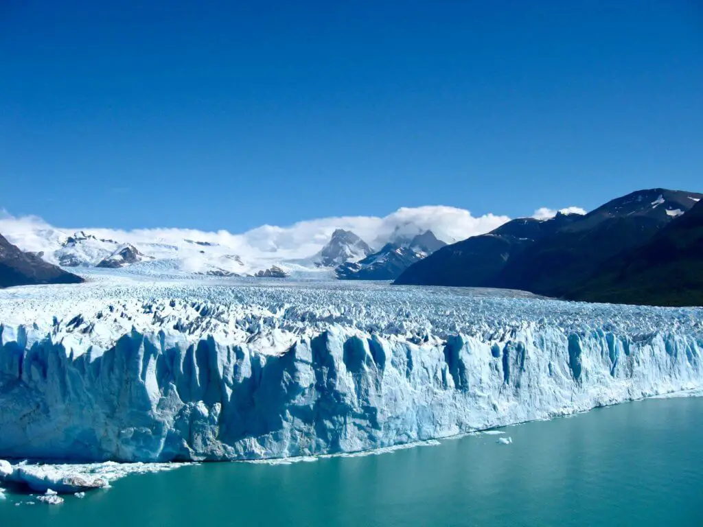 Huge blue Perito Moreno glacier coming off the mountains and into a lake