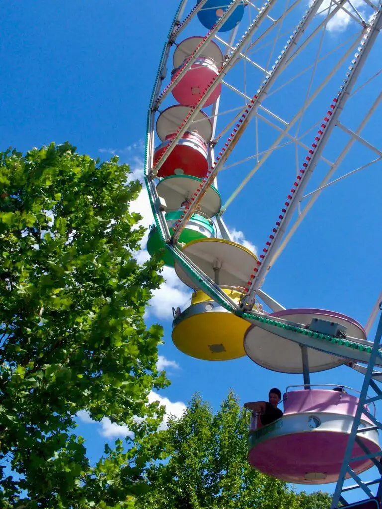 View of ferris wheel cars rising into a blue sky