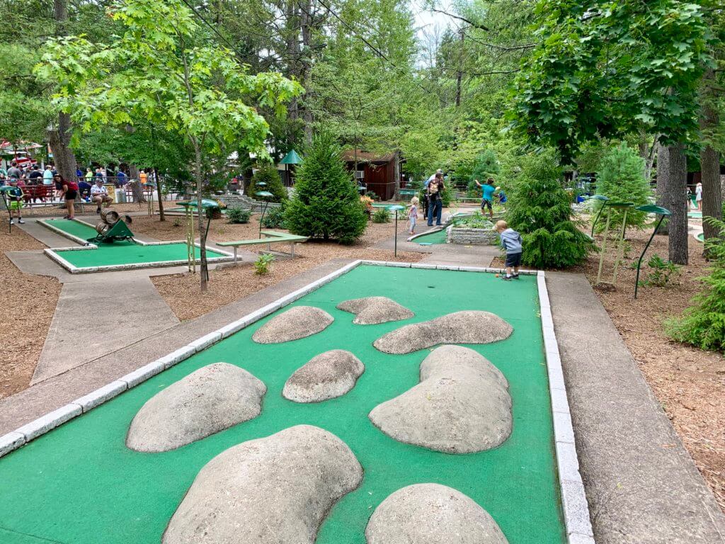 E playing mini golf on a wooded course